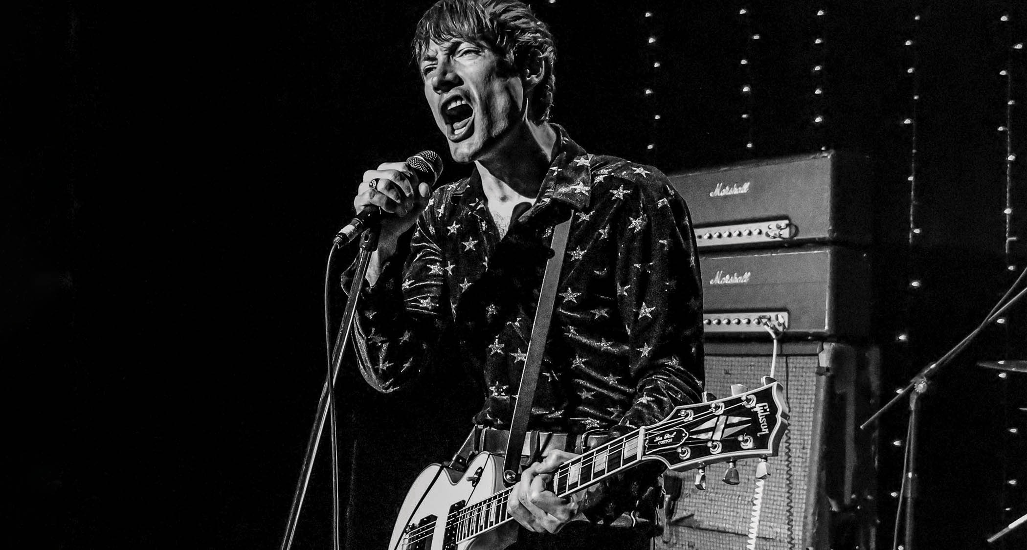 A black and white action shot of Luke Bentham performing with the Dirty Nil