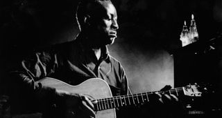 Big Bill Broonzy plays some acoustic blues in this deep contrast B/W archive image.