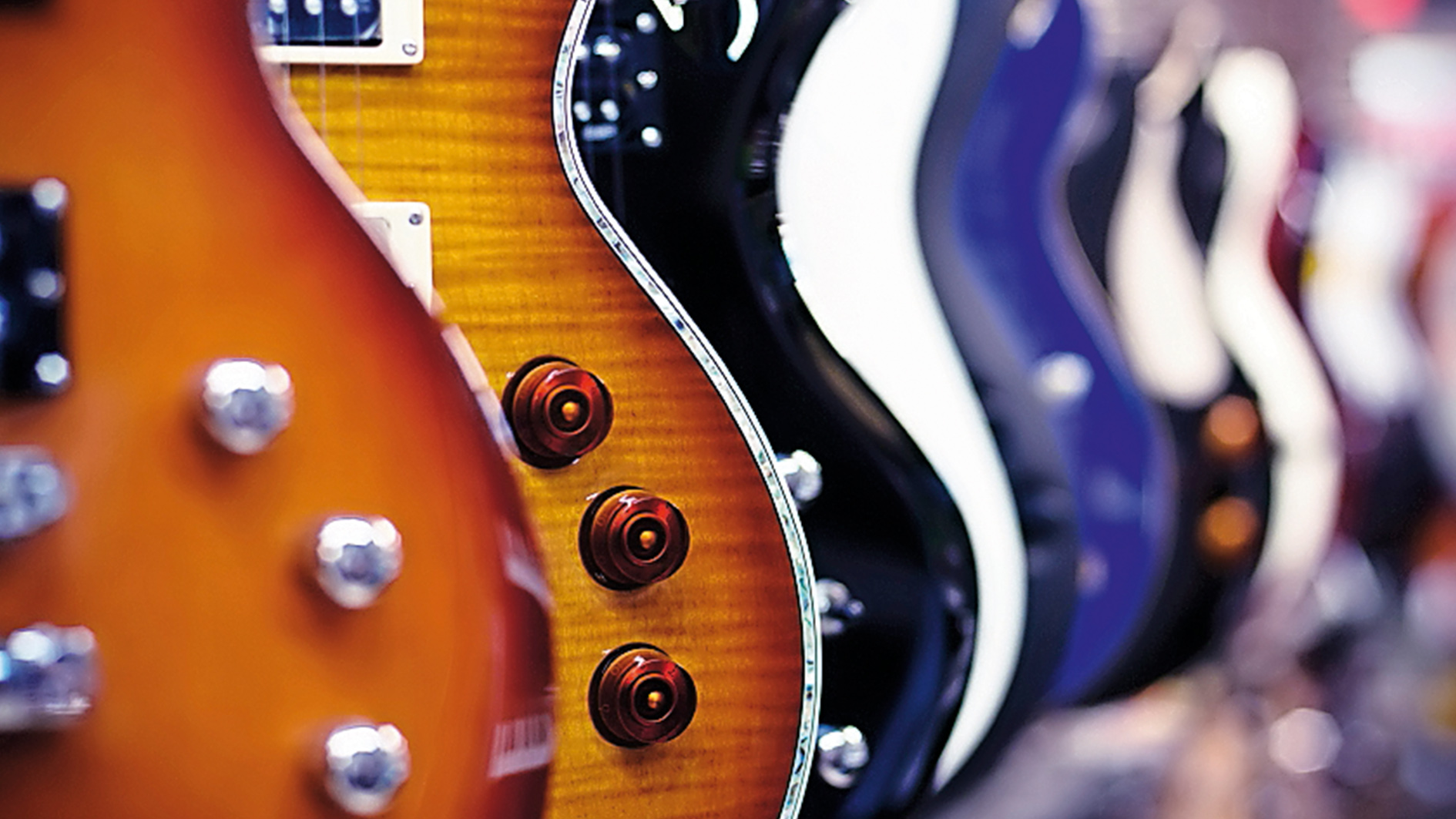 Guitars lined up on the wall of a guitar store