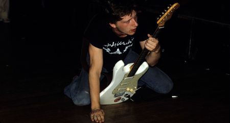 Glenn Tilbrook of Squeeze on his knees, onstage with his white Stratocaster: Tilbrook knows a thing or two about using inventive and interesting chord voicings in the band&rsquo;s songs